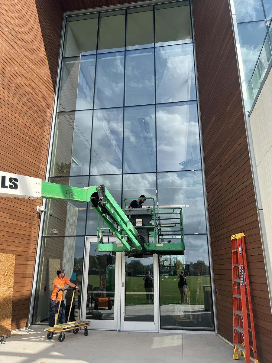 Boring's Glass Co. crew setting a two-story glass curtainwall entry from a lift
