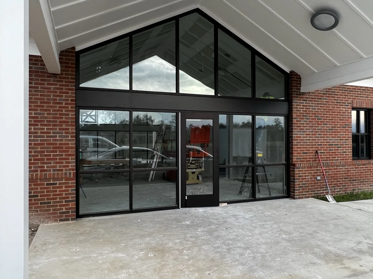Finished black aluminum storefront glazing in a gabled brick entry