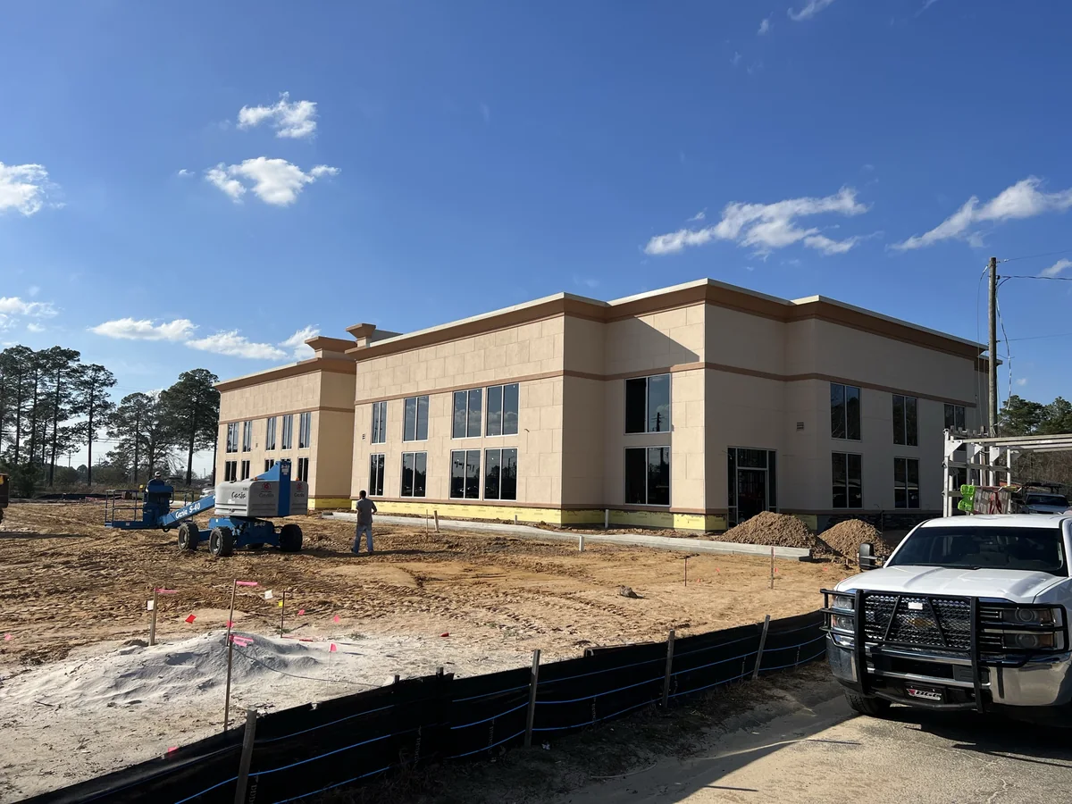 Commercial building mid-construction with glazing crew and lift on site